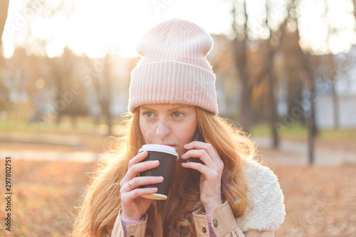 Happy young caucasian woman talking on the phone holding a takeaway coffee cup