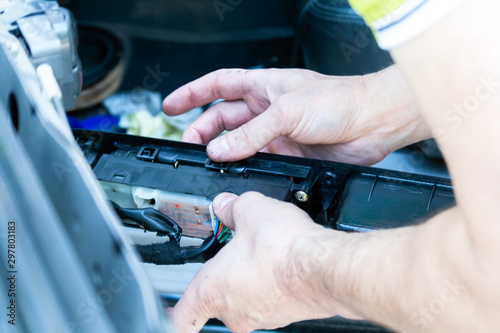 Men's hands hold a disassembled control panel of power windows, central lock and mirrors in order to find the problem and repair it. Searching for a problem at a service station by a qualified worker