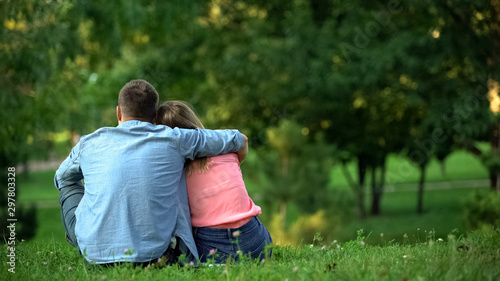 Loving male and female hugging sitting on grass in park, couple togetherness