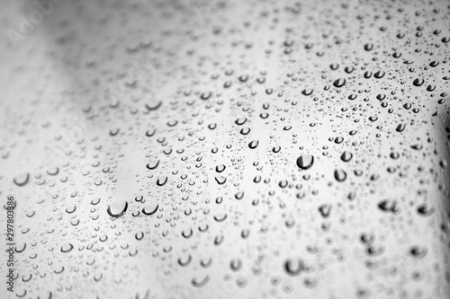 Drops of water on the glass window against a blurred gray sky background on a rainy autumn day. Selective focus