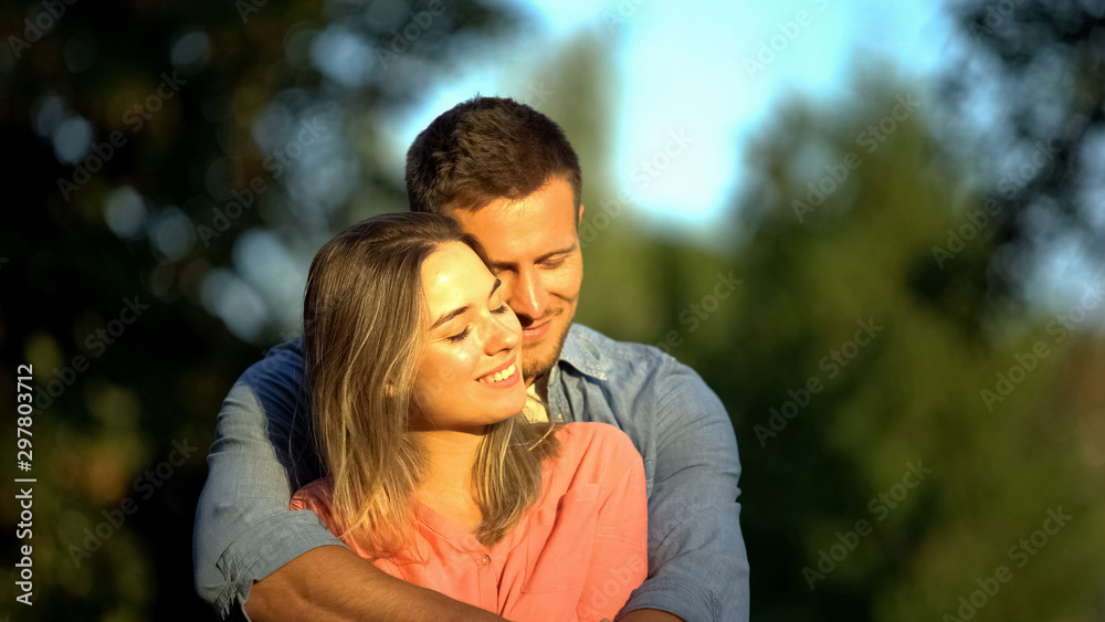 Fototapeta premium Young smiling couple hugging sunny park, candy-flower period, romantic feelings
