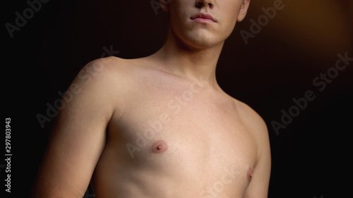 Androgynous man with naked torso against black background, gender expression