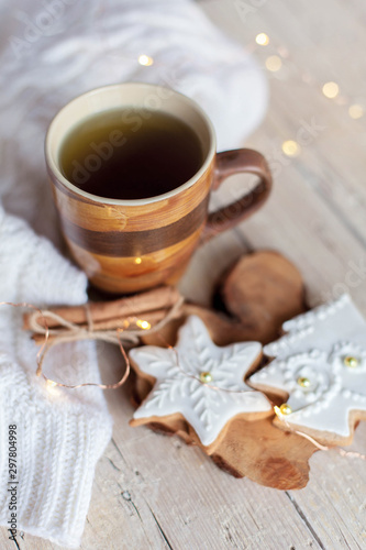 Christmas tea time. Mug of hot beverage, gingerbread cookies at wooden and knitted background. Cozy morning breakfast with homemade sweets and cup. Winter food, drinks, new year lights.