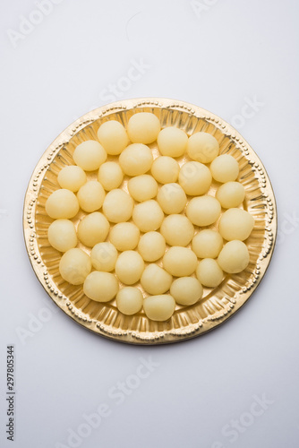 Indian Rasgulla or dry Rosogulla dessert/sweet served in a golden plate. selective focus photo