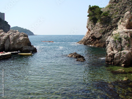 Landscape of the rocky coast of the Adriatic covered with wild vegetation under the rays of summer midday sun under a blue sky.