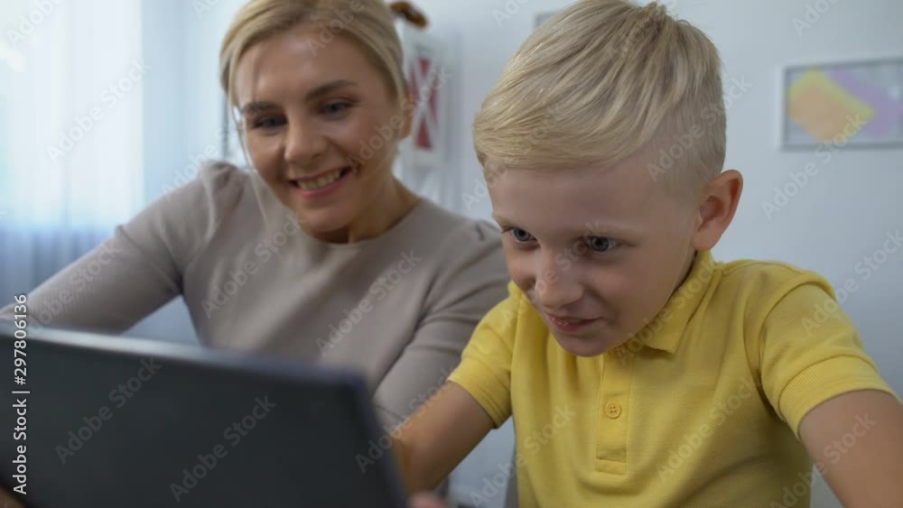 Cheerful mother and son playing game on tablet, trustful relationships, pastime Cheerful mother and son playing game on tablet, trustful relationships, pastime
