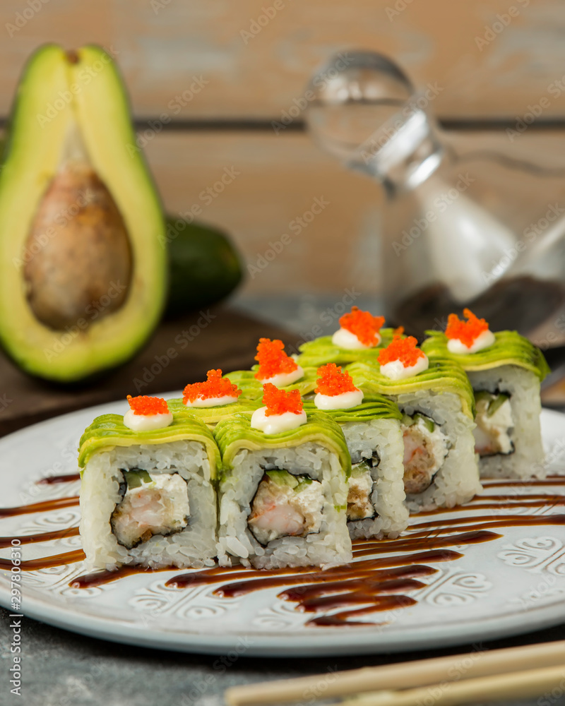 close up of sushi rolls with shrimp, cucumber covered with avocado