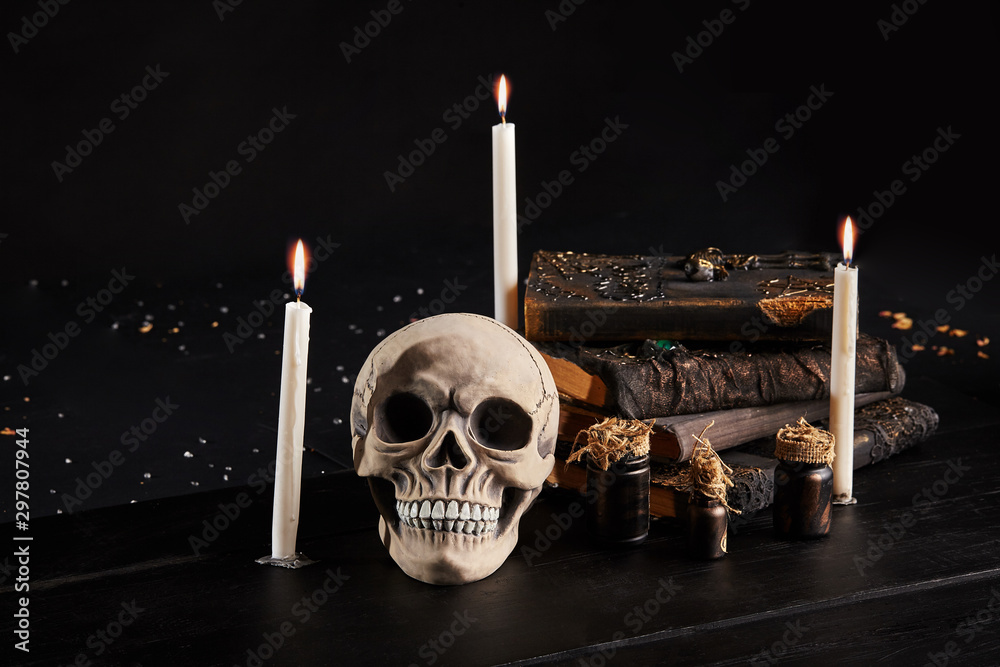 Realistic model of a human skull with teeth on a wooden dark table, black background. Medical science or Halloween horror concept. Close-up shot.