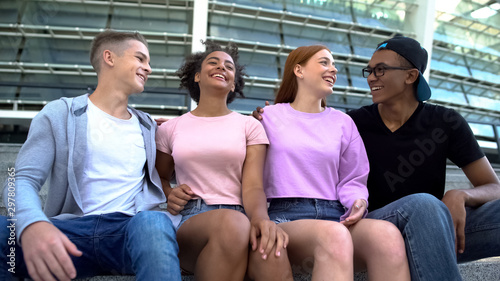 Multi-racial group young people hugging sitting outdoors friendship togetherness