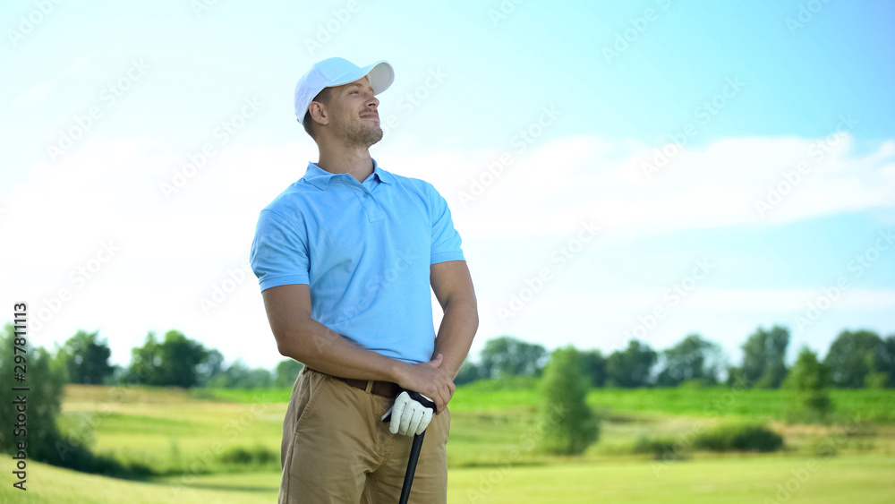 Smiling man golfer with club in hand rejoicing successful shot, sport victory Smiling man golfer with club in hand rejoicing successful shot, sport victory