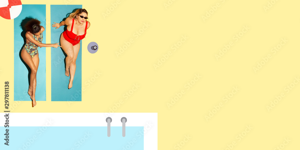 Top view of young caucasian model's resting on beach resort on blue and yellow background as an ocean and sand in bright swimsuit. Copyspace. Concept of summertime, party, chill, vacation, friendship Top view of young caucasian model's resting on beach resort on blue and yellow background as an ocean and sand in bright swimsuit. Copyspace. Concept of summertime, party, chill, vacation, friendship
