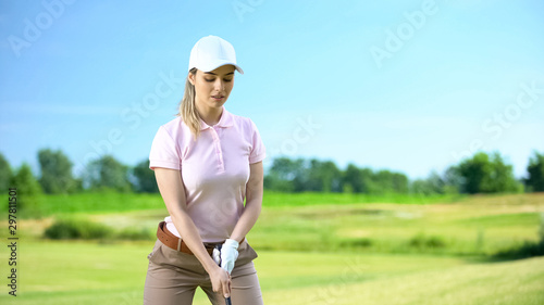 Female in sportswear with golf club ready to hit ball at course, elite hobby