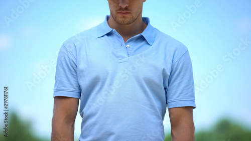 Obraz na plátně Depressed man in blue t-shirt sadly looking down outdoor, feeling desperate