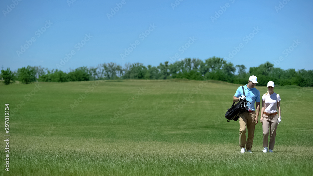 Pair of golfers with clubs bag communicating during course walk after game hobby Pair of golfers with clubs bag communicating during course walk after game hobby
