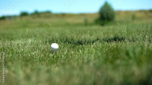 Golf ball on tee at course, professional sport equipment, luxury outdoor hobby