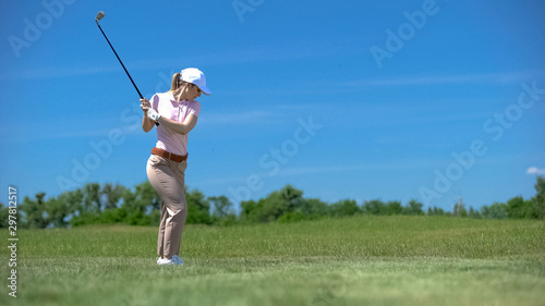 Woman performing backswing position hitting ball on course sport training, hobby