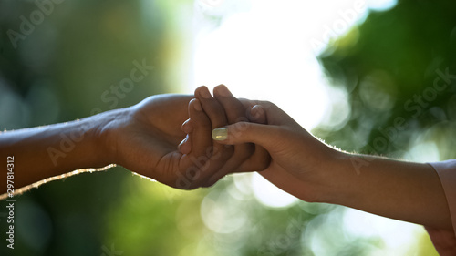 Young couple in love holding hands against park background, trustful relations