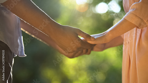 Close up of mixed-race lovers holding hands in park, romantic relationship