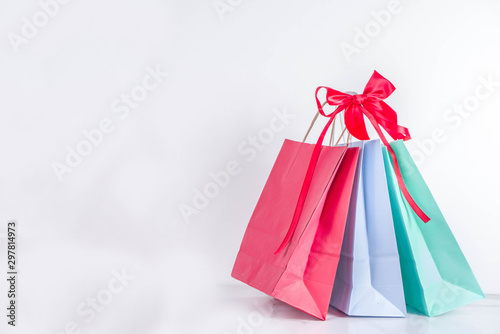 Christmas shopping and sale concept. Buying Christmas gifts. Pastel colored paper bags with xmas and New Year gifts. On white background copy space
