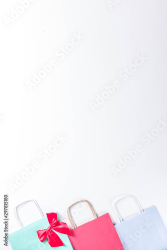 Christmas shopping and sale concept. Buying Christmas gifts. Pastel colored paper bags with xmas and New Year gifts. On white background copy space