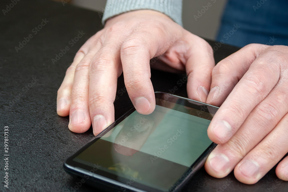 Man reads news on his mobile phone, which lies on the table Man reads news on his mobile phone, which lies on the table