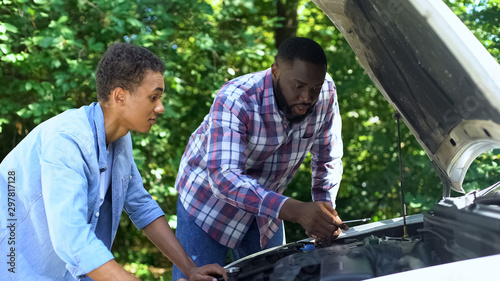 American father explaining car structure to son showing auto parts, togetherness