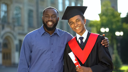 Proud glad father hugging graduating son with diploma, education degree, success