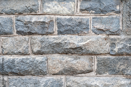 A wall of rough granite bricks with cement grout between them