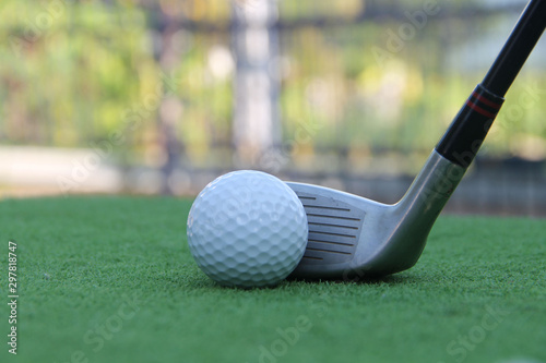 Golf club and golf ball close up in grass field with sunset.