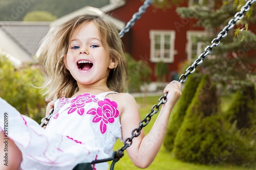 Little child blond girl having fun ona swing