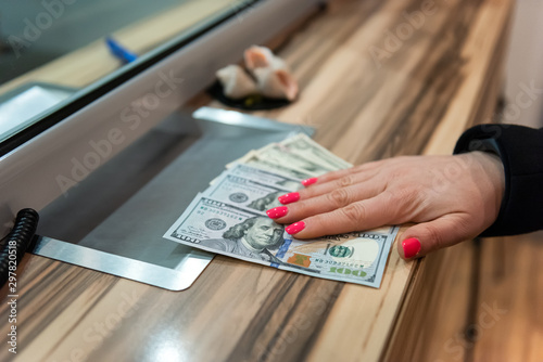 Money exchange concept / Female hand with money at cash desk. Currency exchange concept.