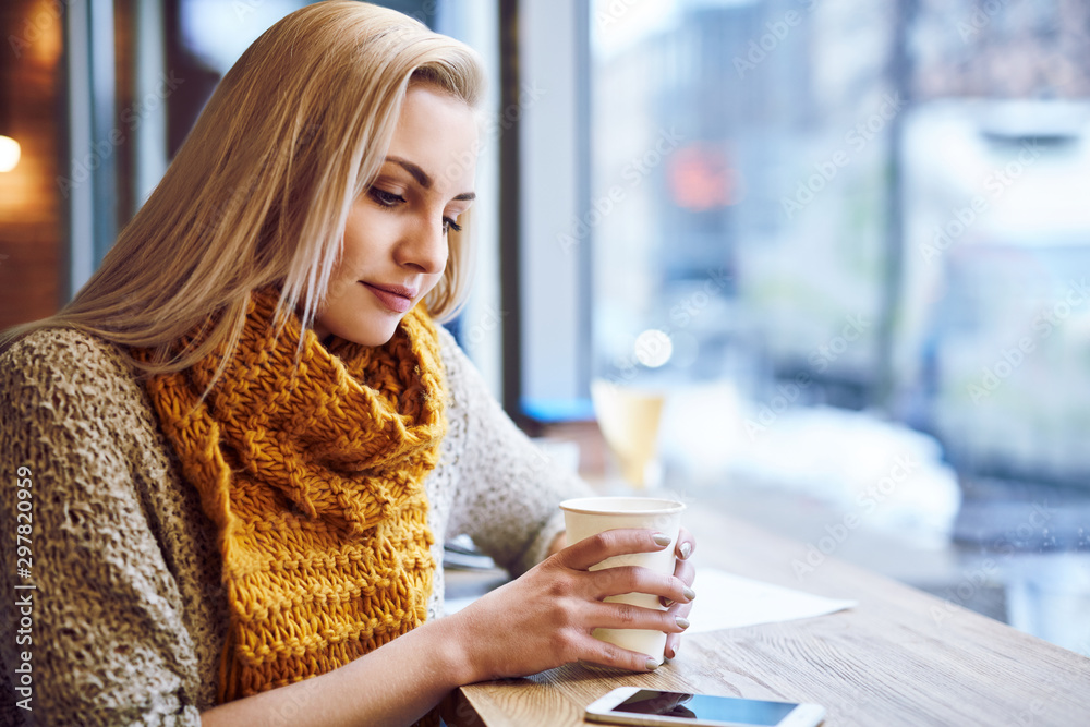 Beautiful young woman warming up in cafe during cold winter day. - obrazy, fototapety, plakaty 