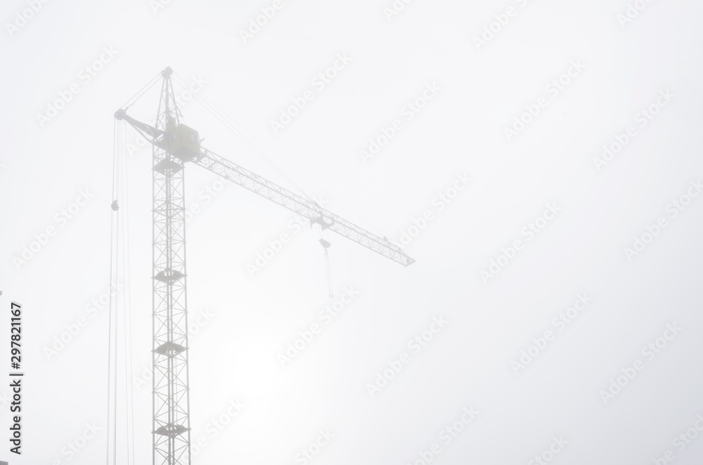 Construction crane in the fog.Calm haze morning at the construction site Construction crane in the fog.Calm haze morning at the construction site