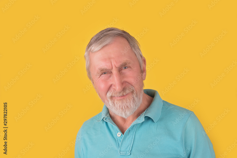Obraz premium Handsome elderly bearded man with grey hair smiling and looking at camera over yellow background