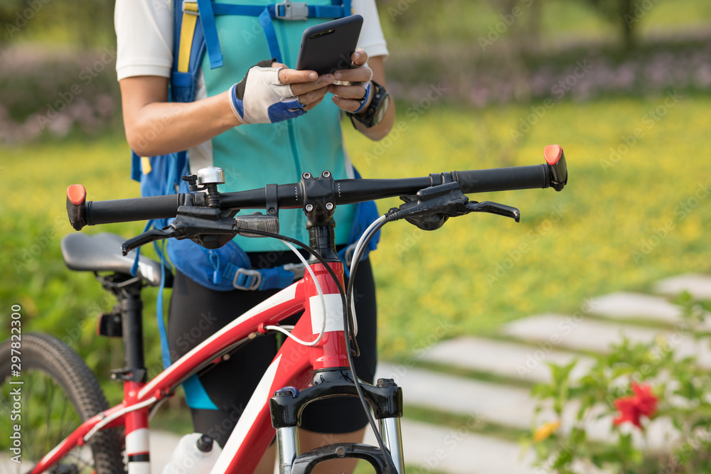 Woman using smartphone while riding bike on sunny day in park Woman using smartphone while riding bike on sunny day in park