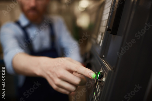 Close-up of manual worker is going to push green button on the machine in the factory