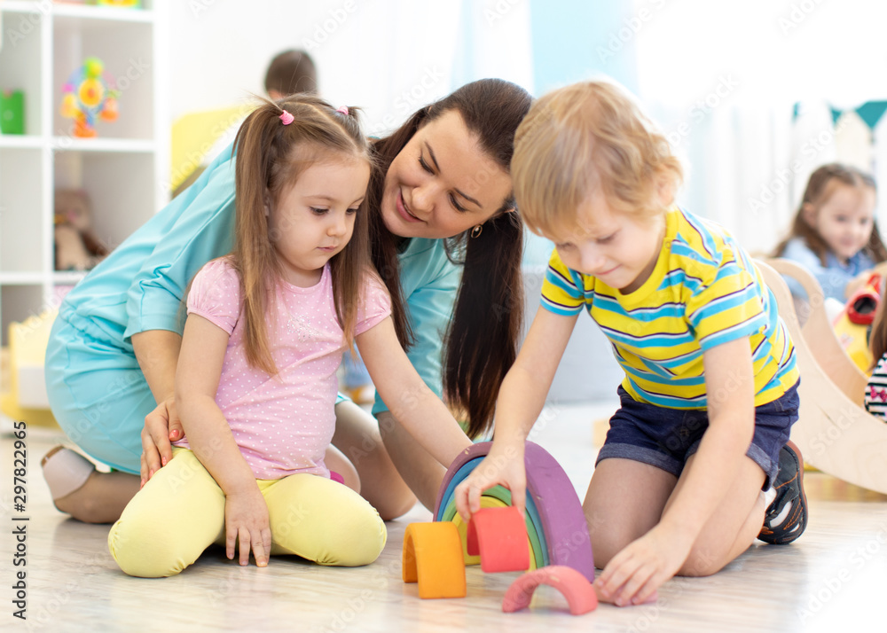 Fototapeta premium Preschool children and kindergarten teacher playing with toys