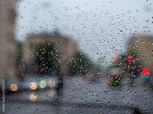 Rainy day city view behind wet window glass
