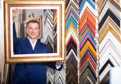 portrait of man seller working with picture frames in atelier photo