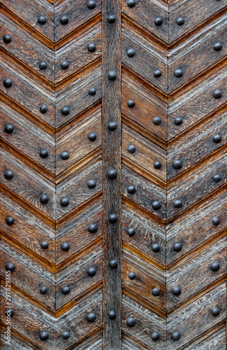 An old-style door made of old worn varnished panels riveted with button-head rivets as a background