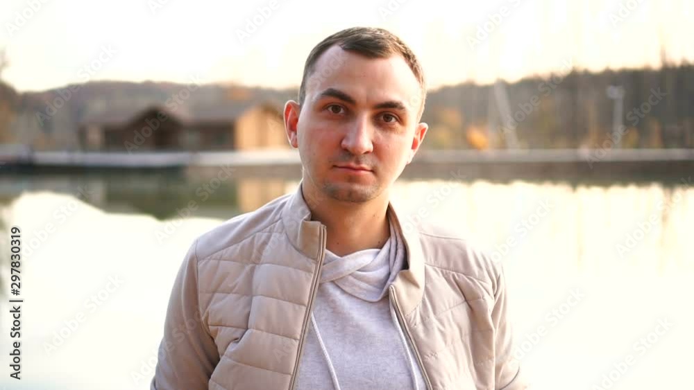 Portrait of a young handsome man in fall clothes. Man wearing white autumn clothes looks without emotion at the camera Portrait of a young handsome man in fall clothes. Man wearing white autumn clothes looks without emotion at the camera