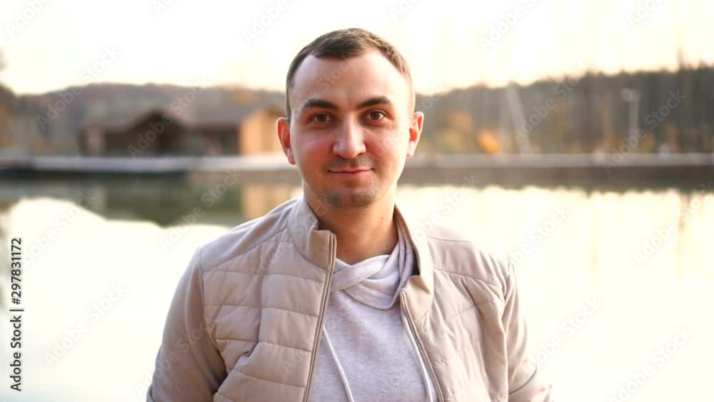 Portrait of a young handsome man in fall clothes. Man wearing white autumn clothes looks at the camera and smiles Portrait of a young handsome man in fall clothes. Man wearing white autumn clothes looks at the camera and smiles