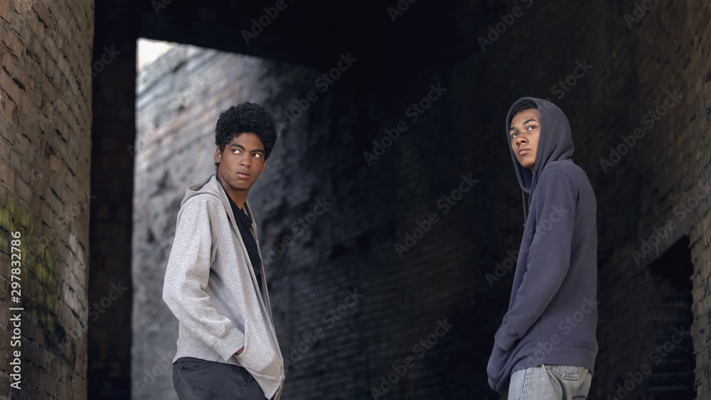 Obraz premium Two african teenagers in hoodie walking city together, dangerous city area