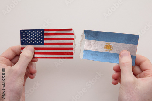 USA and Argentina paper flags ripped apart. political relationship concept