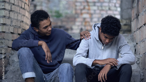 Afro-american teenager trying to make peace with friend, helping boy in need photo