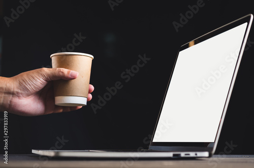 human hand in front of laptop on the table with blank, mockup image of screen