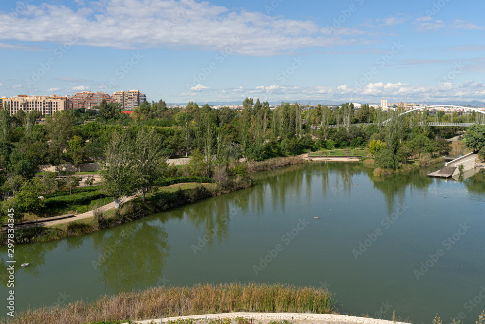 Beautiful green urban park. Public park with green grass fields, trees, waterways and pond. Parque de Cabecera, Valencia, Spain