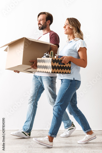 Photo of happy couple holding cardboard boxes while walking