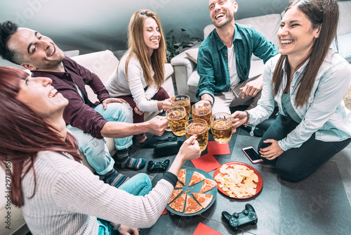 Young millenial friends eating pizza at home after college - Friendship concept with roomates students enjoying time together having fun at shared apartment with tech devices and videogame controllers photo