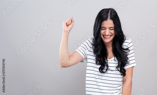 Young woman making a yay gesture on a gray background